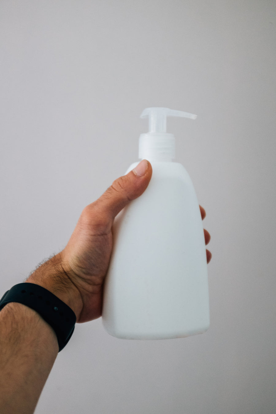 A hand holding a plain skin care bottle